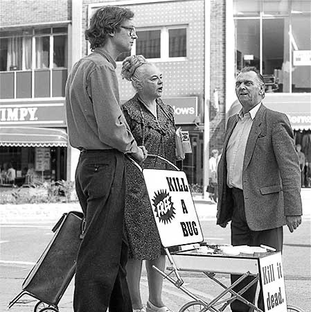 PICTURE: black and white of Ms. Piddington telling the man who wants to kill an insect that he is cruel and yells for the police while Gibson listens.